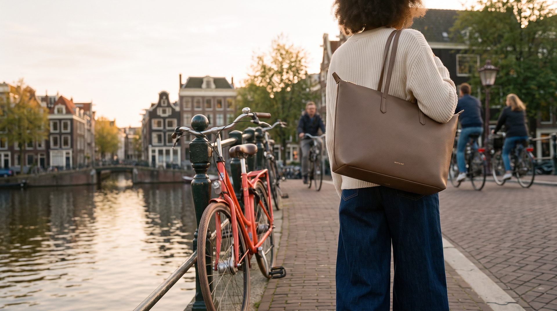 vrouw op de rug gezien met de matt & nat abbi-tas aan een gracht bij zonsondergang