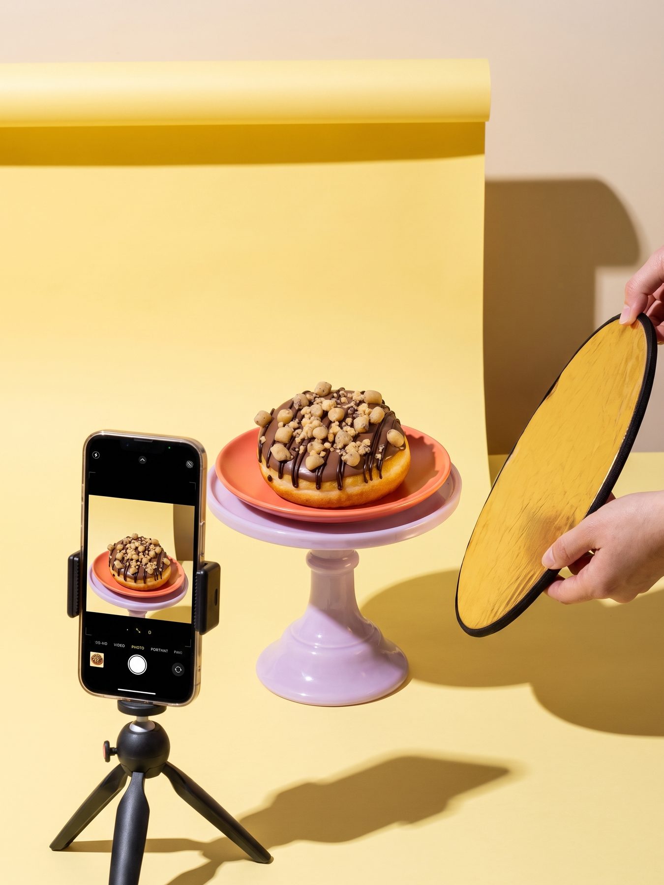 dunkin' cookie dough-donut op een fotoset met een telefoon op statief en een reflectiescherm