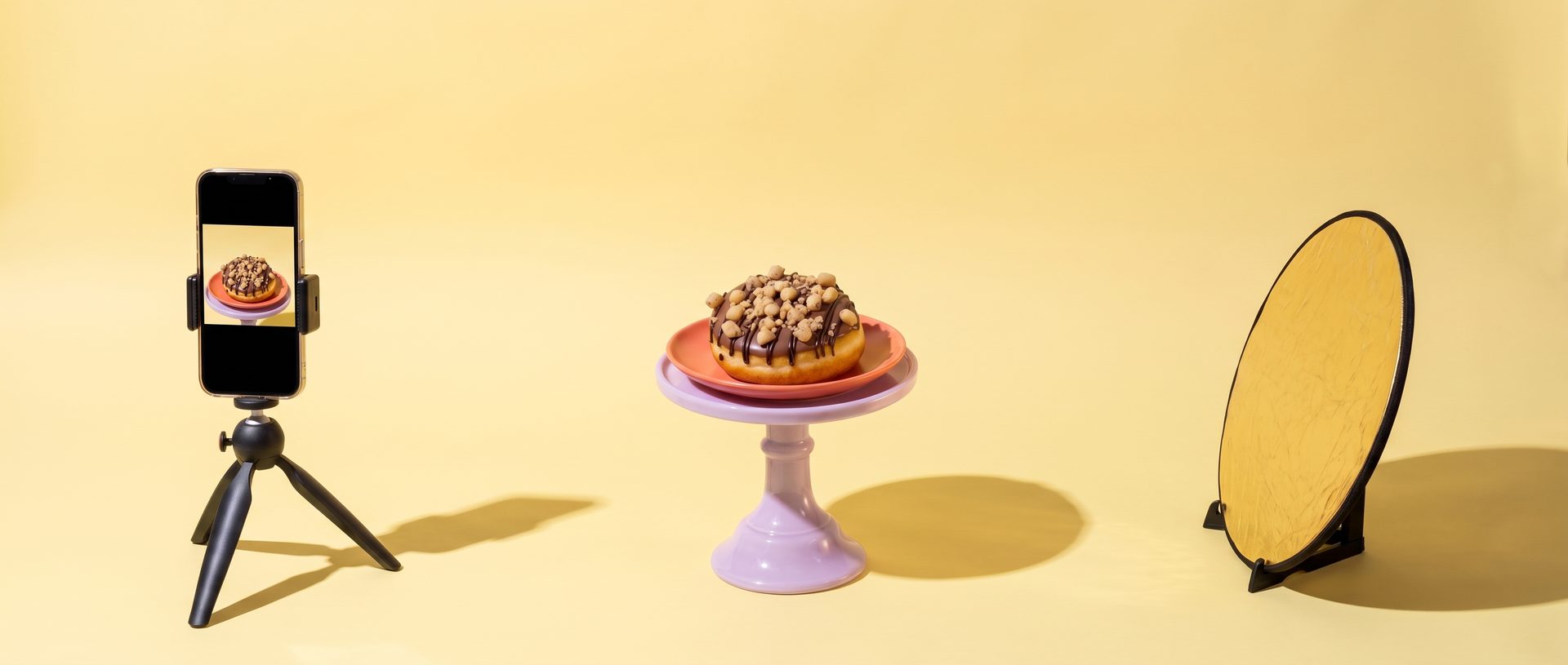 dunkin' cookie dough-donut op een fotoset tussen een telefoon op statief en een reflectiescherm